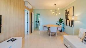 Un salon moderne comprenant un coin repas, un canapé, un téléviseur et une lampe.