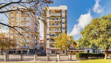 Um edifício residencial com vários andares, varandas, área gramada na frente e céu limpo.
