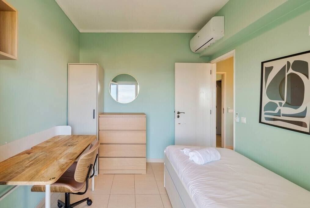 Quarto compacto com cama, escrivaninha, cadeira, guarda-roupa e espelho.