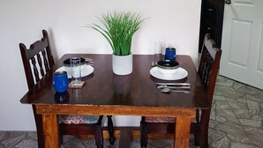 Una mesa de comedor con sillas, un mapa en la pared, una planta en maceta y una puerta al fondo.