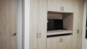 Une pièce dotée d’une étagère intégrée pour la télévision, de meubles en bois et d’une porte.