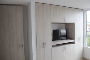 Une chambre dotée d’une grande armoire, d’un téléviseur posé sur une étagère et d’une fenêtre offrant une vue agréable.