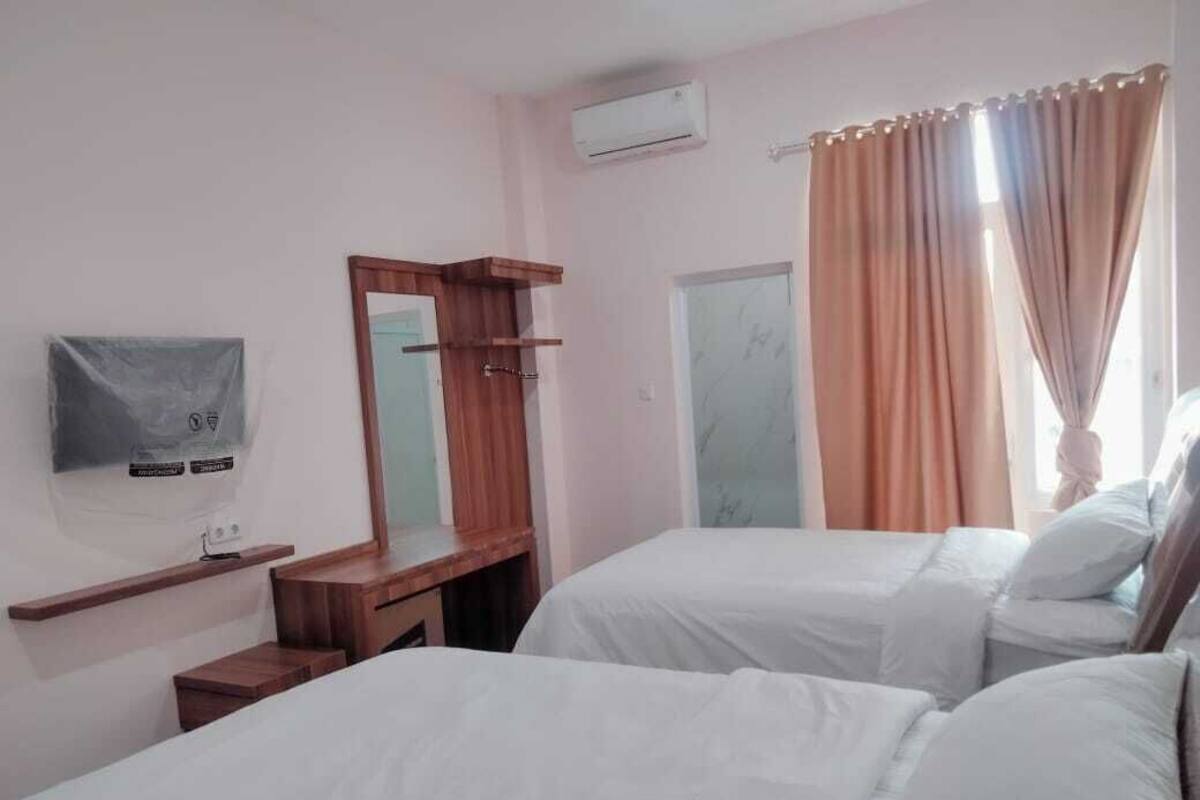 A hotel room with two beds, a TV, a wooden dresser, a mirror, and a window with curtains.