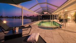 Une piscine extérieure avec des chaises longues et un patio couvert.