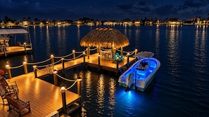 A waterfront resort with a dock, lounge chairs, and a boat. - VRCC Villa Lakualoosa (Cape Coral)