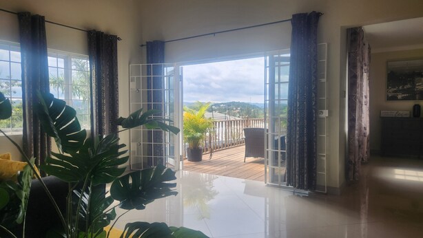 Une pièce spacieuse dotée d’une grande porte-fenêtre coulissante donnant sur un balcon avec vue sur le paysage.