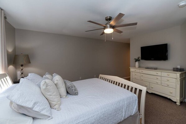 A bedroom with a bed, a ceiling fan, a dresser, and a TV. - Ohana Hideaway- New Rental 2023! 9 min to beach (Cape May)