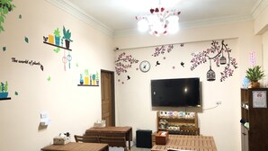 A dining area with wooden tables and chairs, a television mounted on the wall, and decorative wall stickers. - Jiufen Cafe Sleep B&B No.1 Rain House (New Taipei City)