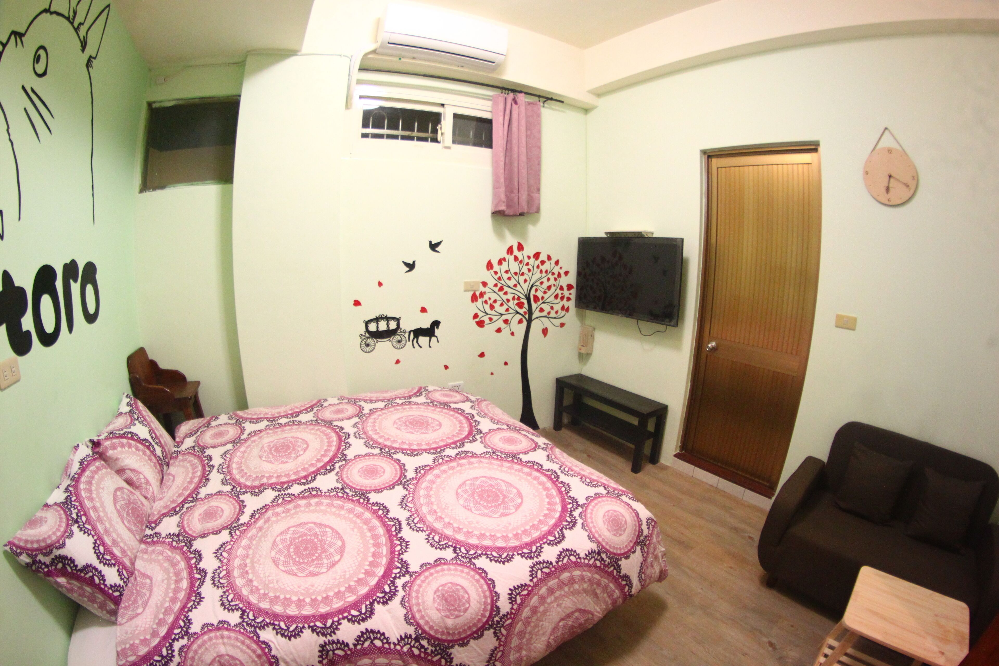 A bedroom with a bed, a wooden bench, a brown sofa, a TV, and a door.