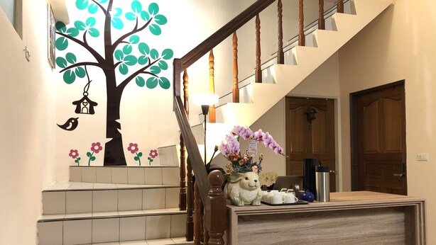 A staircase with a wooden handrail, a wall-mounted tree decal, and a small table with a teapot and cups. - Jiufen Cafe Sleep B&B No.1 Rain House (New Taipei City)