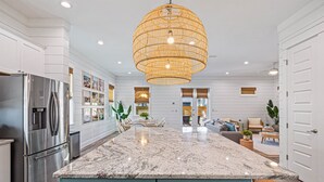 A modern kitchen with a large island, stainless steel appliances, and a hanging light fixture. - My Happy Place Miramar Beach - 6BR Villa, Private Pool and Hot Tub, Golf Cart (Miramar Beach)