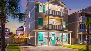 A multi-story residential building with a balcony, a covered porch, and a fenced yard. - My Happy Place Miramar Beach - 6BR Villa, Private Pool and Hot Tub, Golf Cart (Miramar Beach)