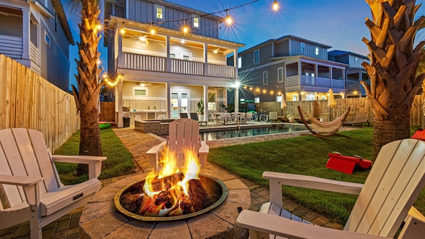 A backyard with a fire pit, outdoor furniture, a pool, and a two-story house with balconies. - My Happy Place Miramar Beach - 6BR Villa, Private Pool and Hot Tub, Golf Cart (Miramar Beach)