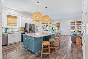 A modern kitchen with a central island, bar stools, and pendant lighting.
