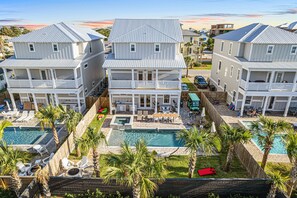 A multi-story hotel with a swimming pool, outdoor seating, and palm trees.