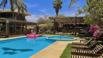 Alberca al aire libre, sombrillas en la alberca y camastros