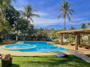 A swimming pool with lounge chairs and palm trees. - Straw Hat Surf Hostel (Puerto Escondido)