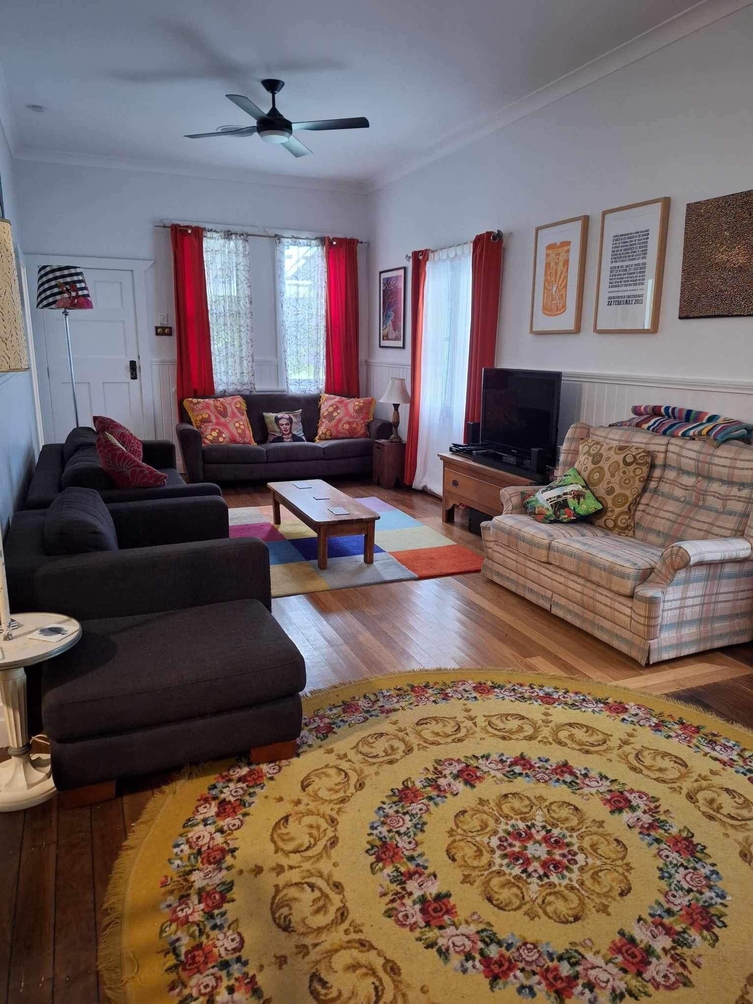 A living room with a sofa, armchairs, a coffee table, a television, and a patterned rug.