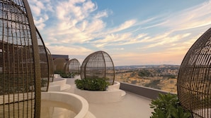 Terraza en la azotea con vistas panorámicas, que incluye varios maceteros y estructuras de mimbre.
