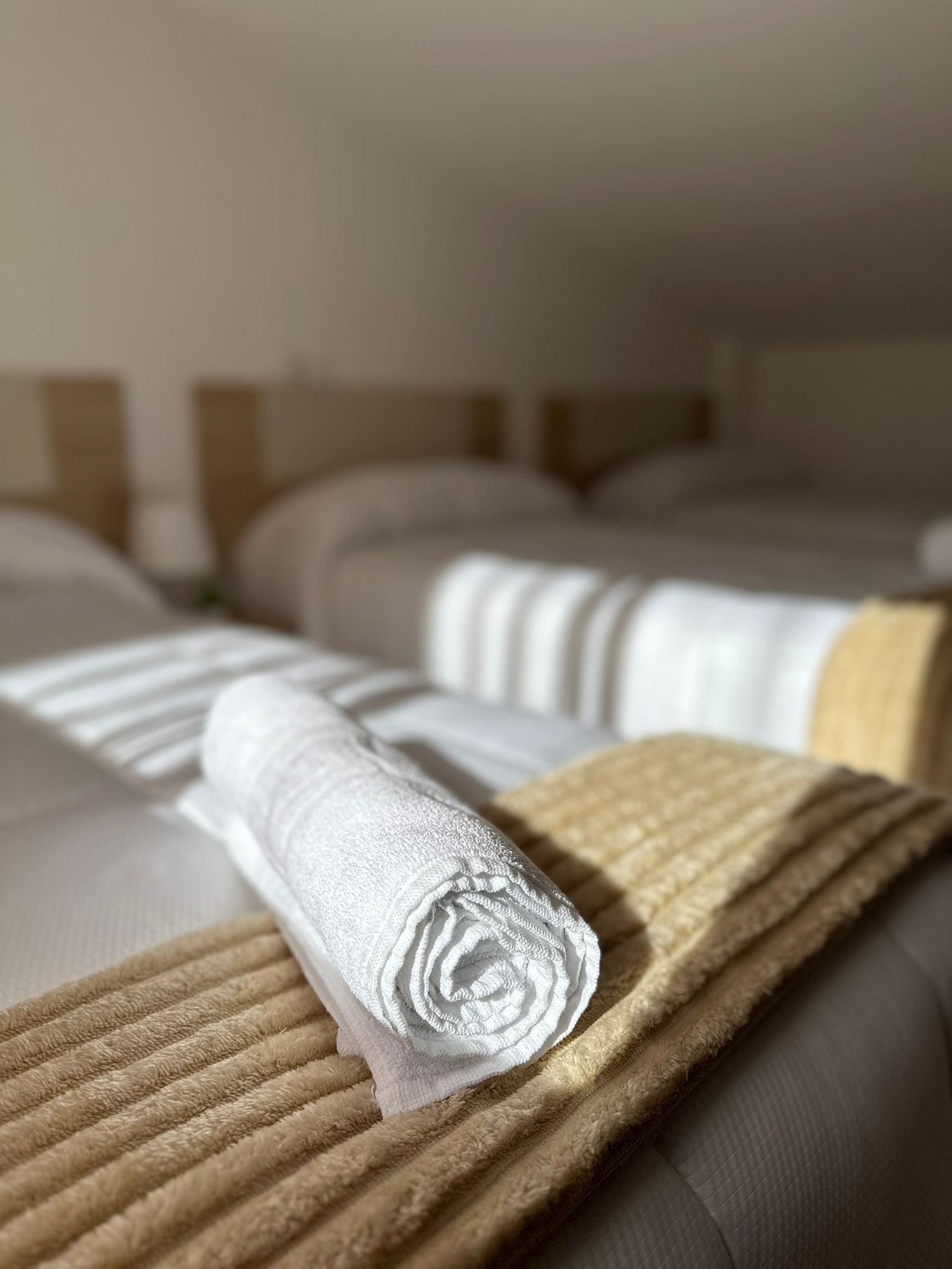 Ett hotellrum med två sängar, var och en med ett vitt täcke och en beige pläd.