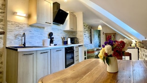 Una cocina con armarios de madera clara, un salpicadero de piedra y una mesa de comedor de madera.