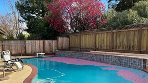 A backyard with a swimming pool, a hot tub, and a wooden fence.