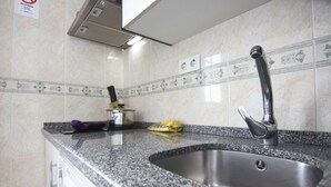 Cozinha com bancada de granito, pia de aço inoxidável e backsplash com azulejos decorativos.