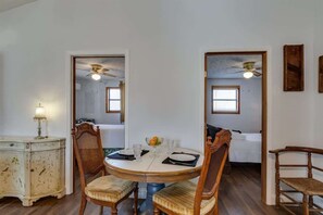 Un coin repas comprenant une table ronde, quatre chaises, une petite table d’appoint avec une lampe et un miroir accroché au mur.