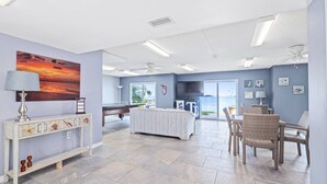 Una habitación amplia con mesa de billar, sillas de mimbre y un cuadro grande de una puesta de sol.