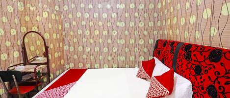 Une chambre d’hôtel avec un lit, une chaise et un rideau à motifs.