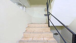 A staircase with beige tiles and a black metal railing. - Hotel O Satria Homestay Syariah (Batam)