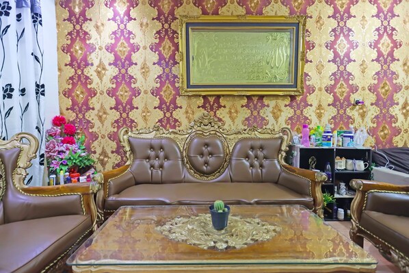 Un salon luxueux avec un canapé en cuir marron, une table basse en verre ornée d’un chemin de table décoratif et un tableau encadré accroché au mur.