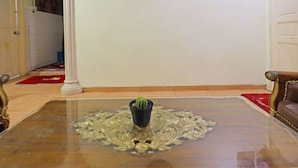 A room with a glass coffee table featuring a decorative glass top, a small potted plant, and a patterned rug. - Hotel O Satria Homestay Syariah (Batam)