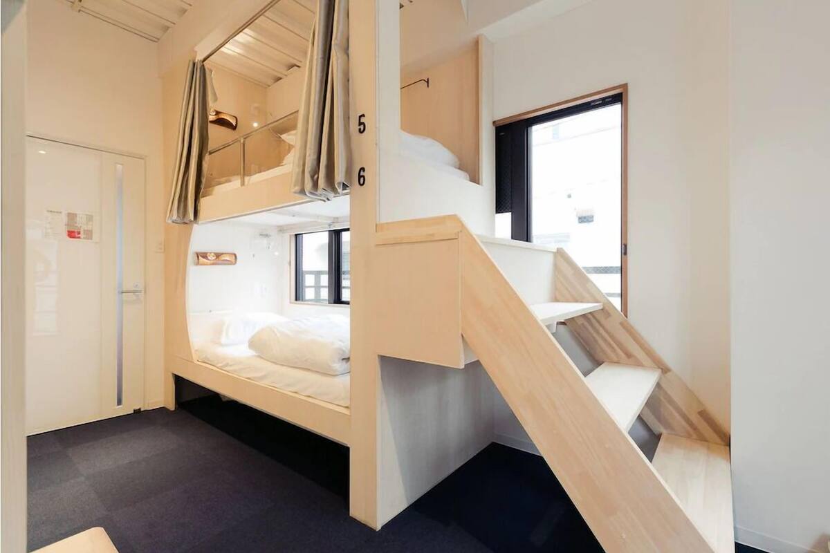 A compact room with a bunk bed, a small desk, and a window.