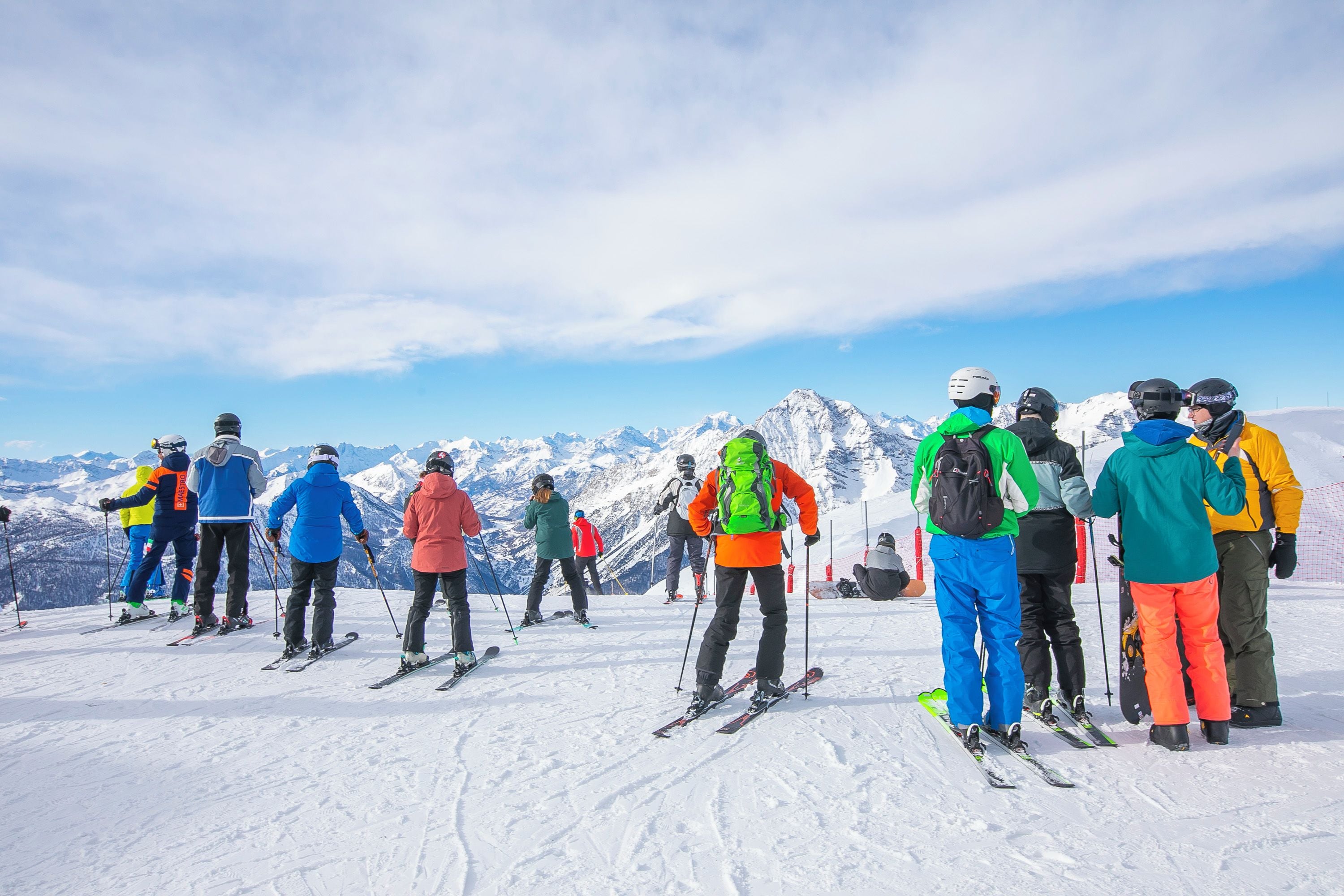 A group of skiers on a snowy mountain slope with a clear sky.