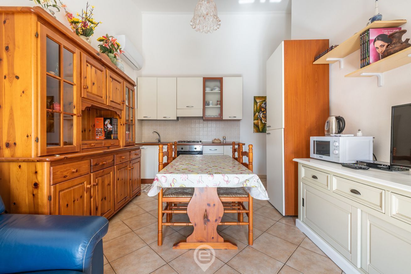 A compact kitchen with wooden cabinets, a dining table, and a microwave.