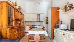 Een kleine keuken met houten kastjes, een eettafel en een magnetron.