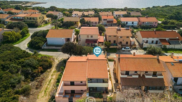 Een kustwoonwijk met huizen met terracotta daken, een helder uitzicht op zee en een kronkelende weg.