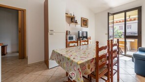 Een eethoek met een tafel gedekt met een tafelkleed, houten stoelen, een televisie en een magnetron.