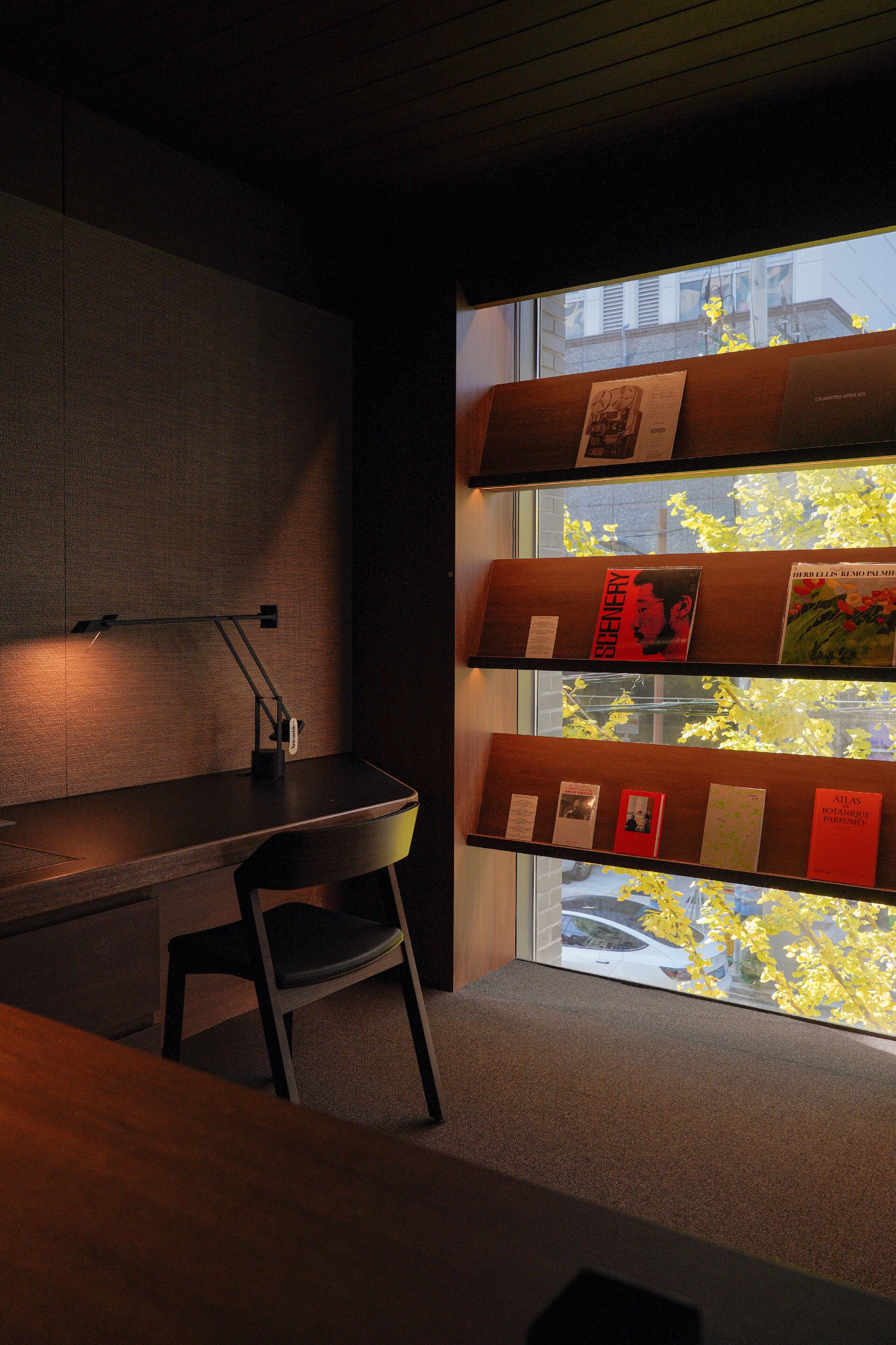 A modern office with a desk, chair, and window with blinds.