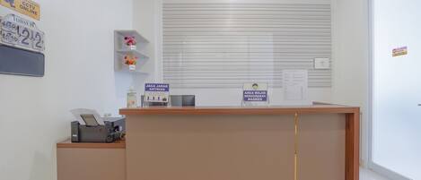 A reception desk with a computer, a sign indicating a mask requirement, and a CCTV sign.