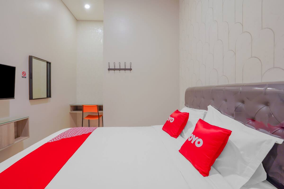 Una habitación de hotel con cama, televisor, escritorio y silla.