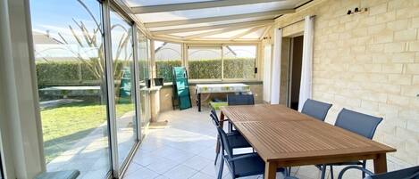 A covered patio area with a table and chairs, a glass door leading outside, and a brick wall.