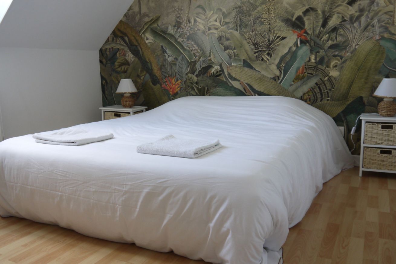 A bedroom with a large bed, a mural on the wall, and a wooden floor.