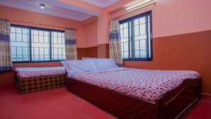 Une chambre avec deux lits, de grandes fenêtres avec des rideaux et une moquette rouge.