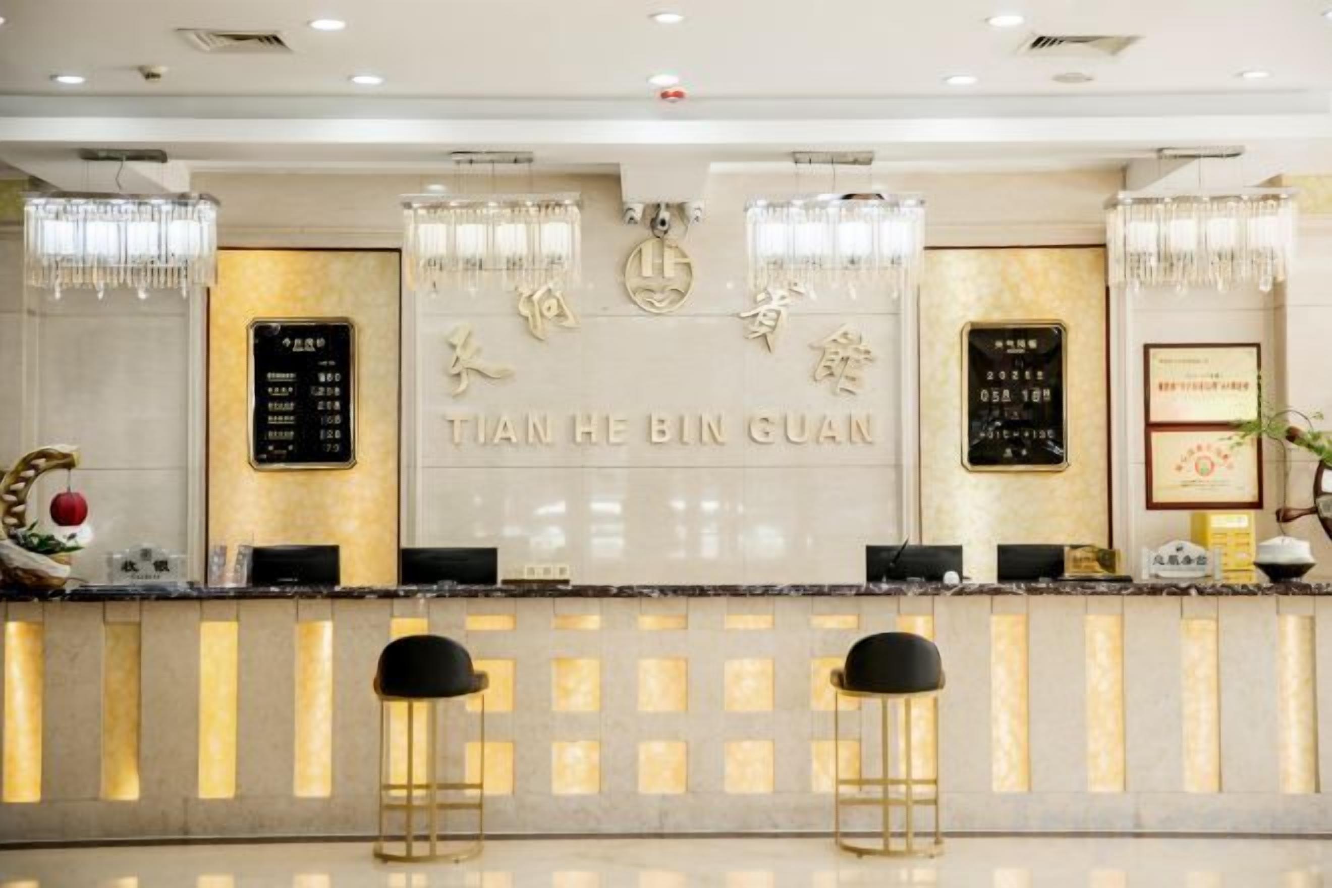 Ein Hotel-Rezeptionsbereich mit Empfangstresen, zwei Barhocker, einer wandmontierten Speisekarte und dekorativen Elementen.