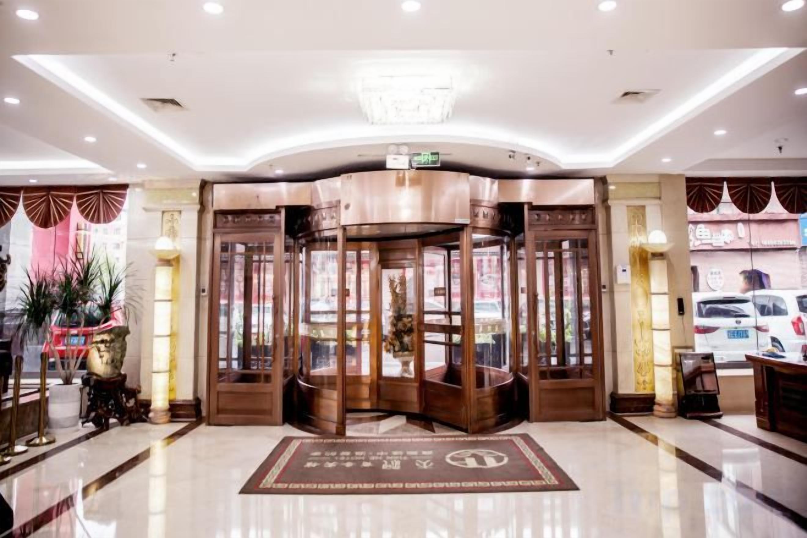 Un hall d’hôtel doté d’une porte tournante, d’un comptoir d’accueil et d’un sol recouvert de moquette.