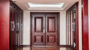 Un pasillo con una puerta doble, una luz en el techo y un suelo de madera pulida.