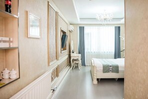 Ein Hotelzimmer mit Bett, kleinem Tisch, Stuhl, Spiegel und einer Kronleuchter.