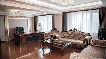 Un salón amplio con piso de madera, un sofá grande, una mesa de centro y un escritorio con una silla.